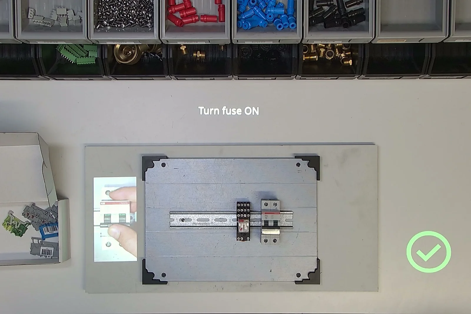Instruction to switch on the fuse, with an image of the component projected next to the cabinet and a check mark after the step