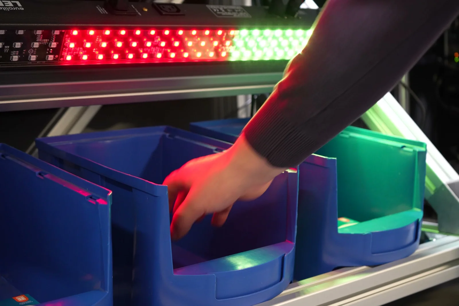 An operator reaches into the wrong bin: the DMX light turns red before the wrong part ends up in the kit